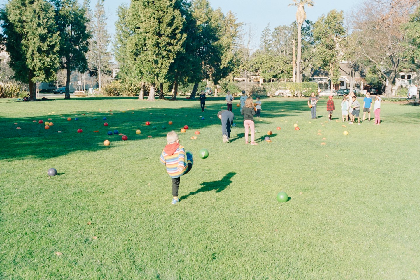 Personas jugando con pelotas y conos naranjas en un campo de césped.
